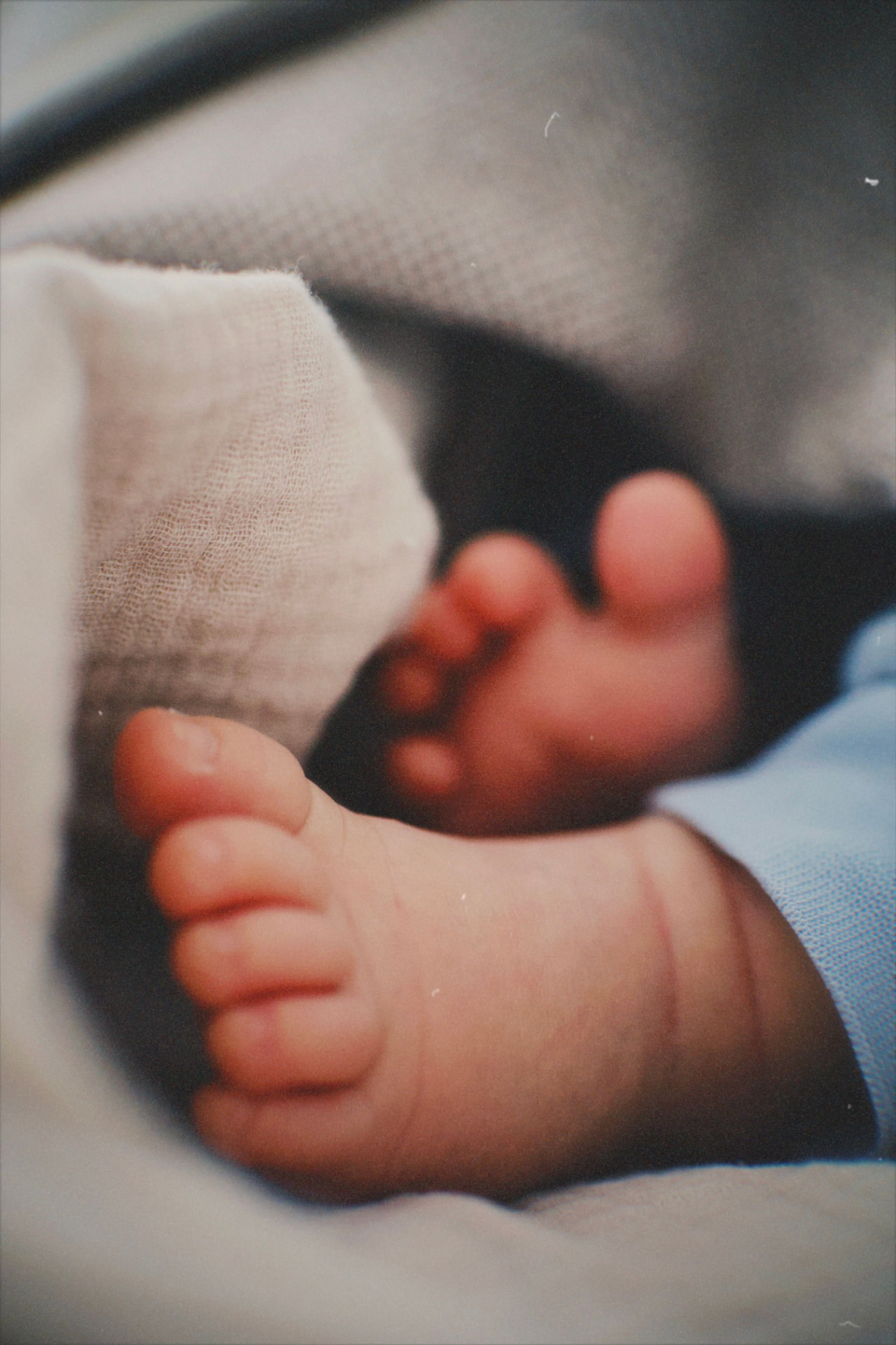Pieds d'un nouveau-né reposant sur des langes en lin crème